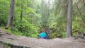 Man sitting in forest fallen rock. Stock footage. Young traveler looks at frightening collapse in rocky landscape of