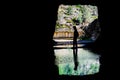 Man sitting in front of the exit to a tunnel, silhouette reflected in a shallow pond; Hetch Hetchy reservoir area, Yosemite Royalty Free Stock Photo