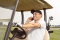 Man sitting in a golf cart and talking on phone Royalty Free Stock Photo