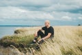 A man sitting on grass and admiring beauty of the coast