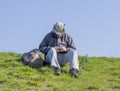 Man sitting on grassy bank cutting fishing line and preparing hi