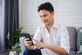 Man sitting on gray sofa using smartphone with smiling face, lifestyle concept Royalty Free Stock Photo