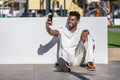 Man Sitting on the Ground Taking a Selfie