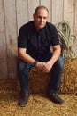 Man sitting on hay bale in a barn Royalty Free Stock Photo