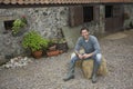 Man Sitting On Haybale Outside Stable