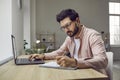 Man sitting at his desk at home, studying online, using his laptop and taking notes Royalty Free Stock Photo