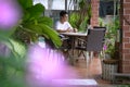 Man sitting at his house patio with garden view, working on his laptop. Work from home concept