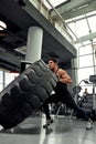 Man sitting on his toes holding a pair of battle ropes for workout. guy at the gym working out with fitness rope.