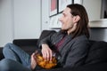 Man sitting at home indoors eating crisps Royalty Free Stock Photo