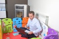 Man sitting inside baby playpen working with laptop and taking notes at home