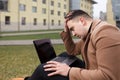 Man sitting with a laptop and depressed because of work. Pensive student holds his head