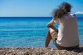 Man is sitting lonely from the back and looking to the Mediterranean blue sea. Horizontal. Royalty Free Stock Photo