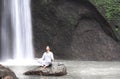 Man sitting in meditation yoga on rock at waterfall Tibumana Royalty Free Stock Photo