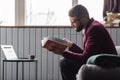 Man sitting near coffee table and reading book about astrology of money Royalty Free Stock Photo