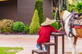 Man sitting near horse and him wear hat.