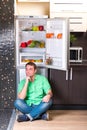 The man sitting next to open refrigerator Royalty Free Stock Photo