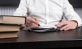 Man sitting at office desk with books or codes and taking notes in diary. Man hands closeup. Planning or information Royalty Free Stock Photo