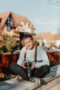 Man Sitting in Old European City And Holding Photo Camera. Contemporary Stylish Blogger And Photographer. Handsome man Royalty Free Stock Photo