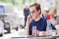Man Sitting in Outside Coffeehouse Talking on Phone