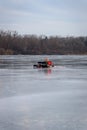 Man sitting on bench alone ice fishing on fozen lake in winter