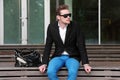 An attractive man sitting down outside wearing jeans and a blazer Royalty Free Stock Photo