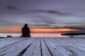 Man sitting on the pier and watching the sunset Royalty Free Stock Photo