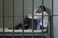 Man Sitting In Prison Cell