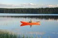 Man sitting in a red canoe on a lake in Finland at sunset Royalty Free Stock Photo