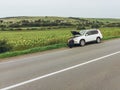 Man sitting on road near broken car. trying stop car for help