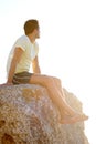 Man, sitting or rock and cliff in nature for travel, adventure or scenery with sunshine, thinking and view. Person