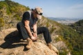 Man sitting on a rock in the nature carving a wooden stick Royalty Free Stock Photo