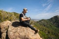 Man sitting on a rock in the nature carving a wooden stick Royalty Free Stock Photo