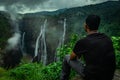 Man sitting at rock watching the beautiful waterfall stream at evening Royalty Free Stock Photo