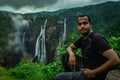 Man sitting at rock watching the beautiful waterfall stream at evening Royalty Free Stock Photo