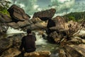 Man sitting at rock watching the beautiful waterfall stream long exposure shot at evening