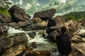 Man sitting at rock watching the beautiful waterfall stream long exposure shot at evening