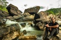 Man sitting at rock watching the beautiful waterfall stream long exposure shot at evening