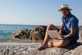 Man sitting on the rocks and using laptop on beach Royalty Free Stock Photo
