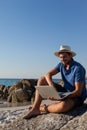 Man sitting on the rocks and using laptop on beach Royalty Free Stock Photo