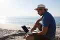 Man sitting on the rocks and using laptop on beach Royalty Free Stock Photo