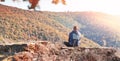 Man sitting on a rocky ledge overlooking a scenic mountain landscape Royalty Free Stock Photo
