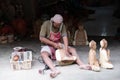 a man is sitting in a shop making wooden carvings of animals