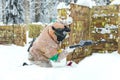 Man sitting on snow behind wooden fortification playing paintball Royalty Free Stock Photo