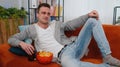 Man sitting on sofa eating chips and watching interesting TV serial, football game online at home Royalty Free Stock Photo