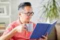 Man sitting on sofa and reading book at home Royalty Free Stock Photo