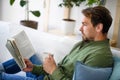 Man sitting on sofa and reading book at home, lockdown concept. Royalty Free Stock Photo