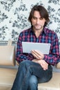 Man sitting in sofa using electronic tablet Royalty Free Stock Photo