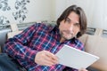 Man sitting in sofa using electronic tablet Royalty Free Stock Photo