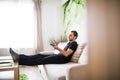 Man sitting on a sofa watching tv holding remote control at home Royalty Free Stock Photo