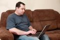 Man sitting on sofa and working at laptop at home Royalty Free Stock Photo